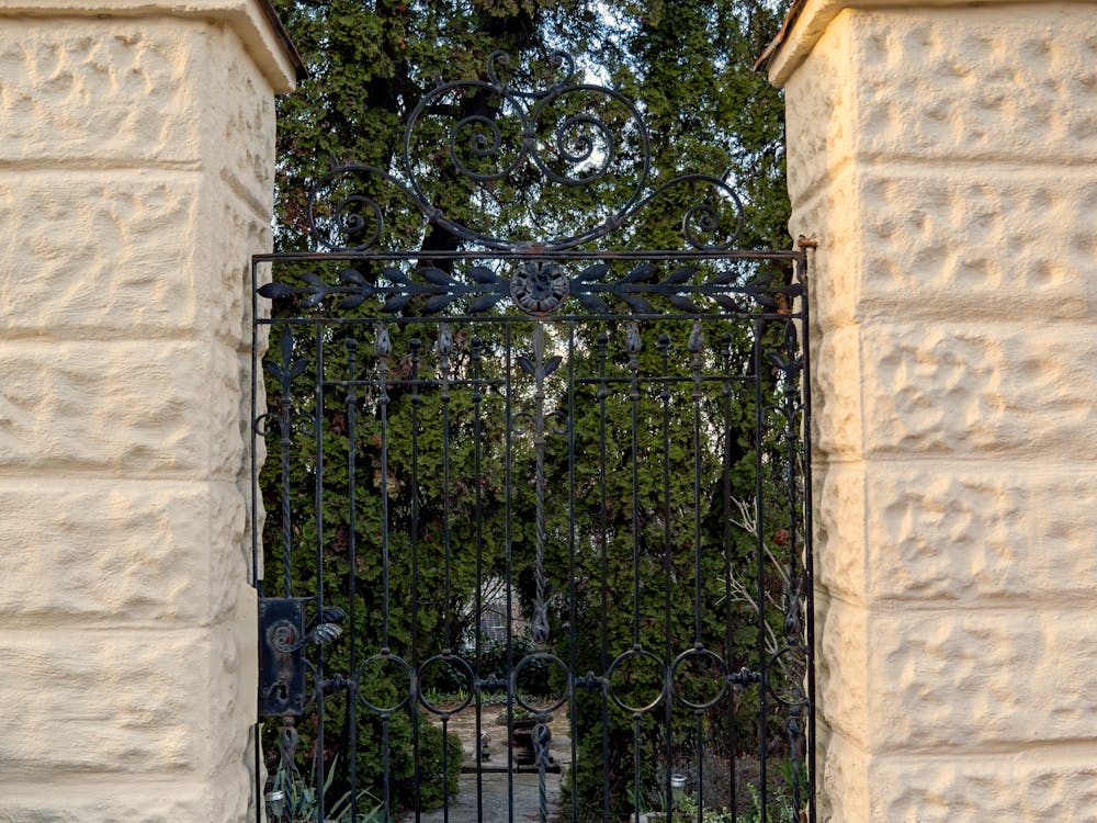 Ornate wrought iron gate between stone pillars