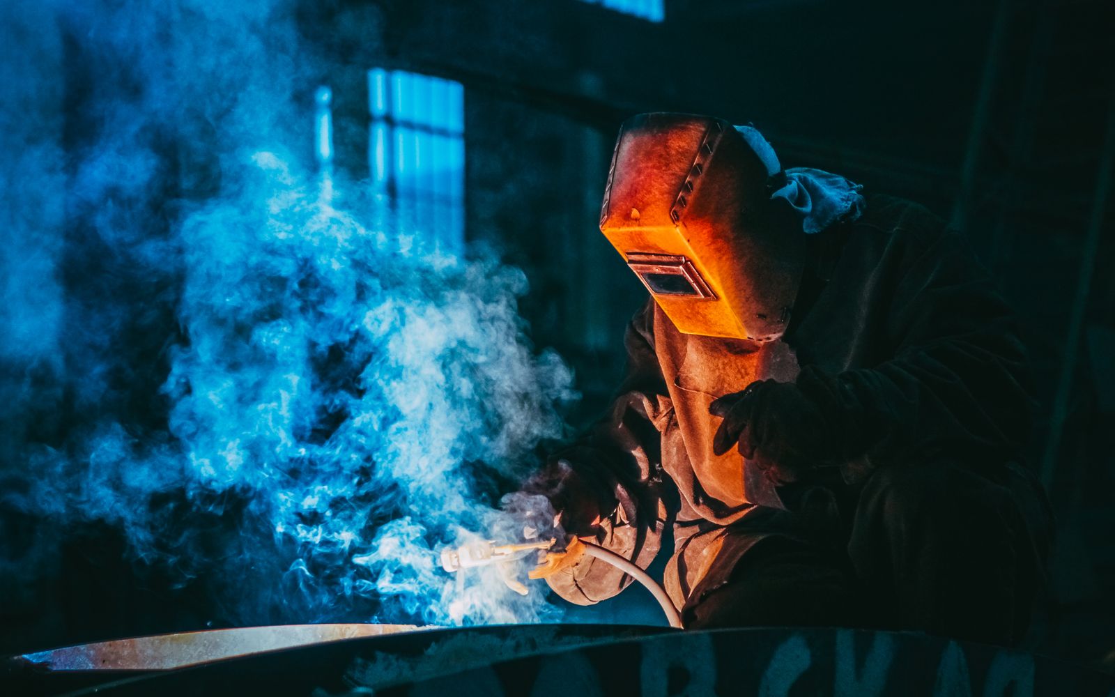 Welder in protective gear working in the shop